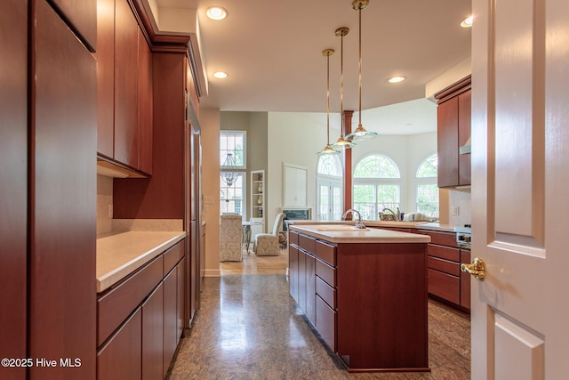 kitchen featuring hanging light fixtures, open floor plan, light countertops, recessed lighting, and a center island with sink