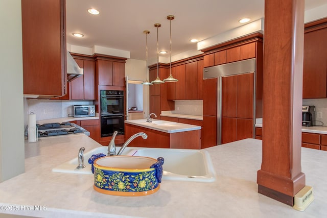 kitchen with dobule oven black, light countertops, paneled refrigerator, under cabinet range hood, and stainless steel gas cooktop