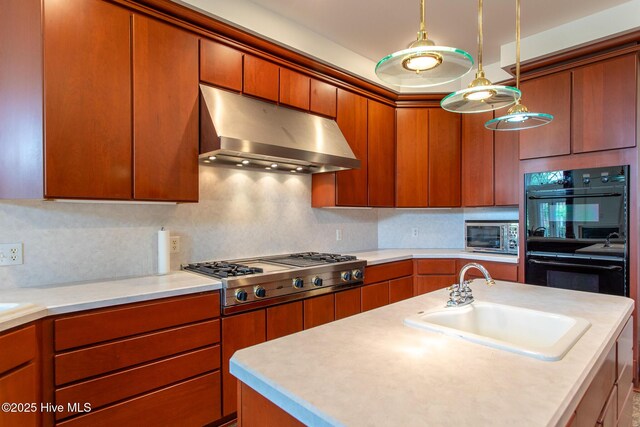 kitchen featuring light countertops, under cabinet range hood, a sink, and stainless steel appliances