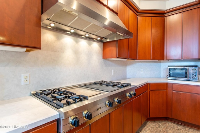 kitchen with stainless steel gas cooktop, tasteful backsplash, range hood, and light countertops