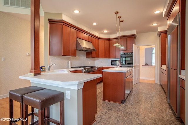 kitchen with range hood, a peninsula, visible vents, a sink, and brown cabinets