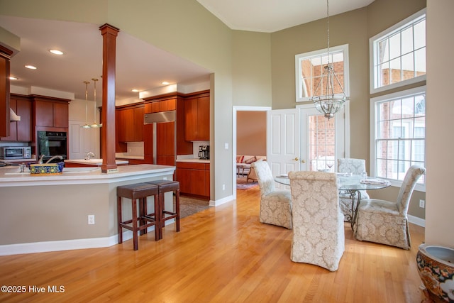 dining space featuring baseboards, a towering ceiling, a chandelier, and light wood-style floors