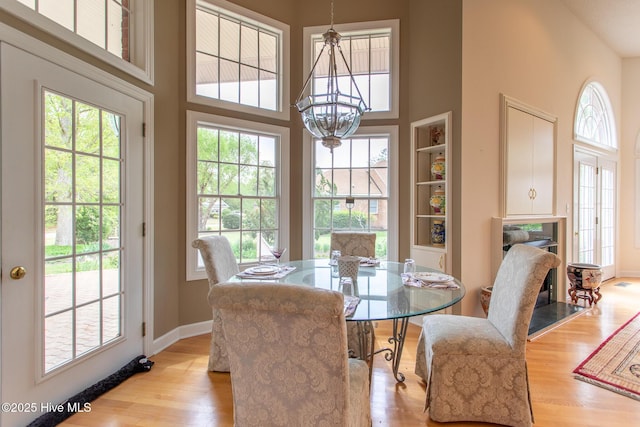 dining area with a chandelier, a towering ceiling, baseboards, and wood finished floors