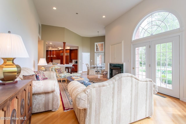 living area featuring light wood finished floors, a towering ceiling, and recessed lighting