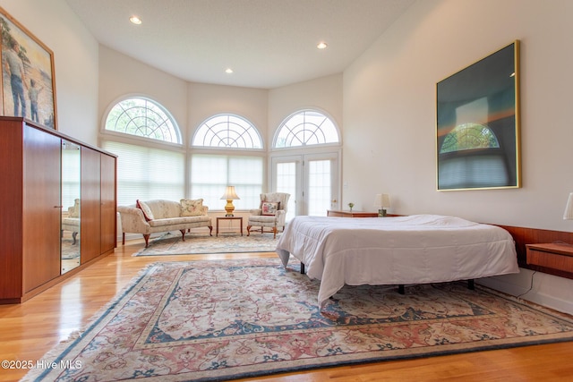 bedroom featuring wood finished floors, a towering ceiling, and recessed lighting