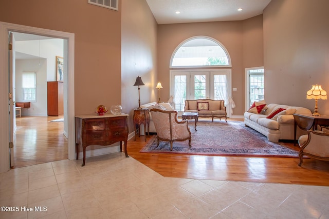 tiled living room featuring plenty of natural light, a towering ceiling, baseboards, and visible vents