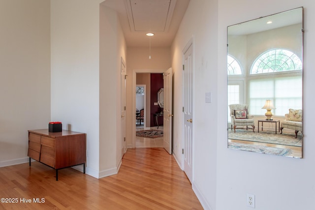 hallway with light wood-style floors, attic access, baseboards, and recessed lighting