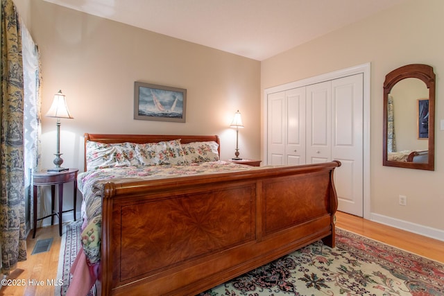 bedroom with visible vents, light wood-style flooring, a closet, and baseboards