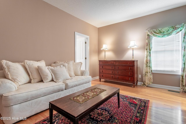 living area featuring visible vents, baseboards, and wood finished floors