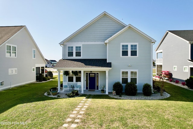 view of front of property featuring a front yard, roof with shingles, and covered porch