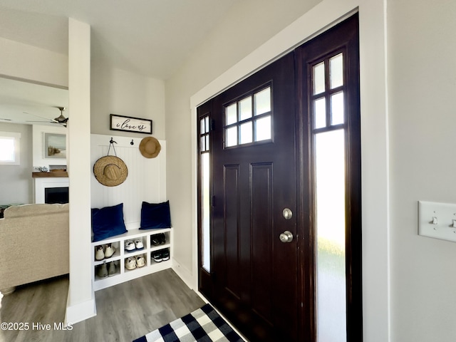 entryway featuring baseboards, dark wood finished floors, a fireplace, and ceiling fan