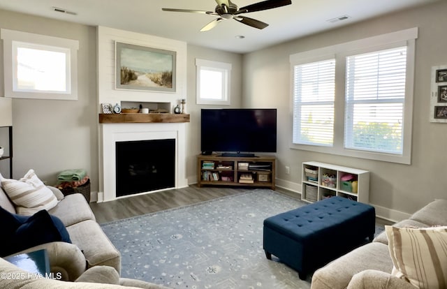 living area featuring a large fireplace, baseboards, a ceiling fan, and visible vents