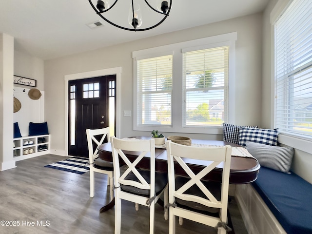 dining space with visible vents, wood finished floors, a healthy amount of sunlight, and a notable chandelier
