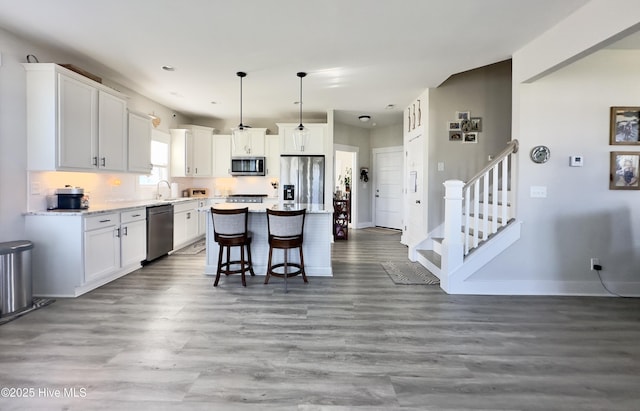 kitchen with white cabinets, stainless steel appliances, baseboards, and a kitchen bar