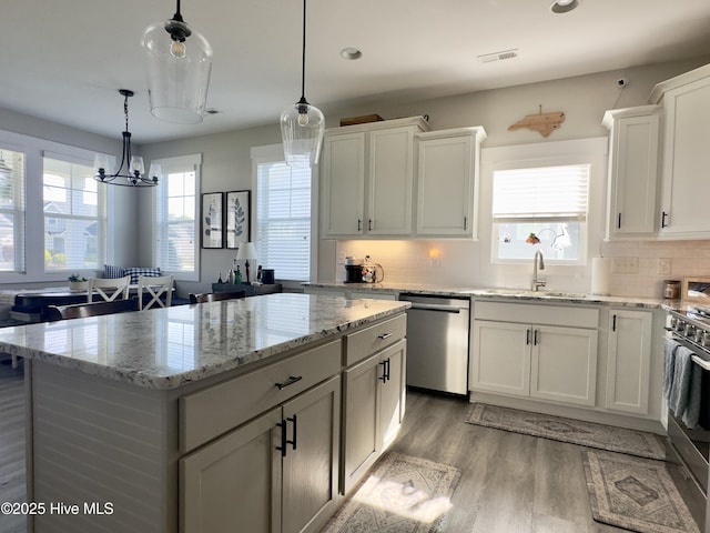 kitchen featuring a center island, a sink, light wood-style floors, stainless steel appliances, and white cabinets