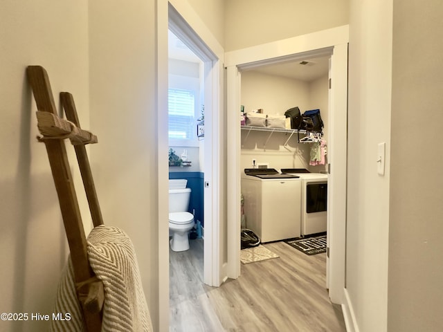bathroom with washing machine and dryer, toilet, and wood finished floors