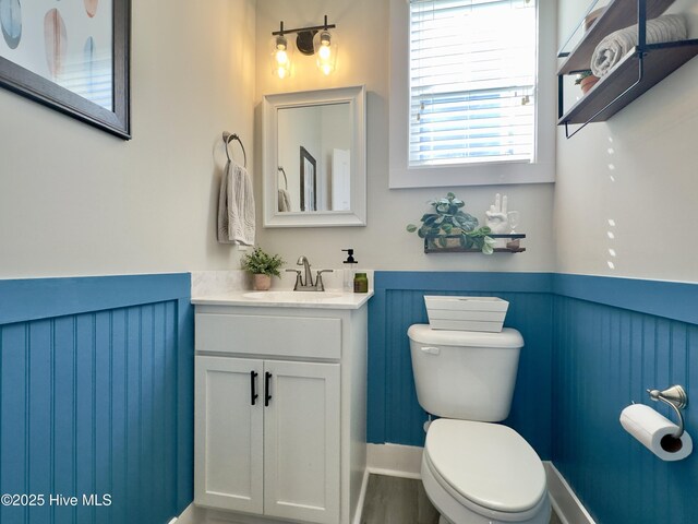 bathroom featuring vanity, toilet, and wainscoting