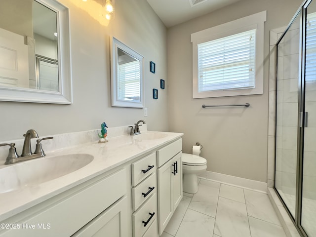 full bathroom featuring double vanity, toilet, a tile shower, a sink, and baseboards