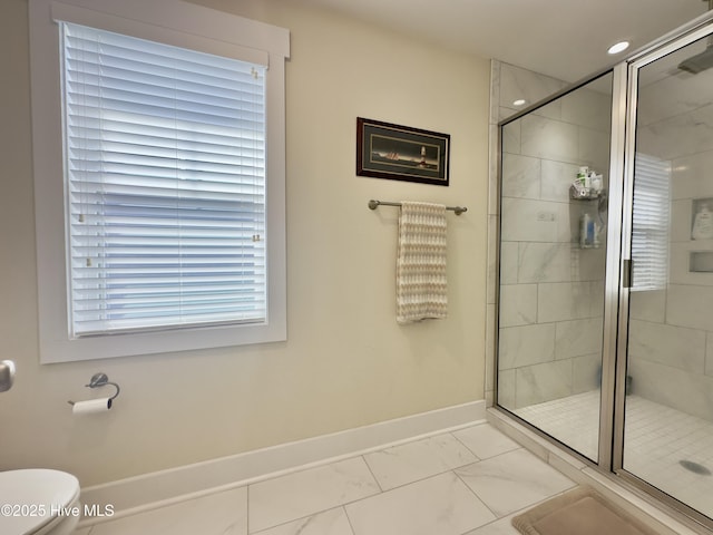 bathroom featuring marble finish floor, baseboards, a stall shower, and toilet