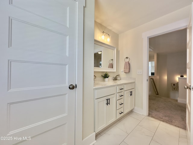 full bathroom with double vanity, marble finish floor, baseboards, and a sink