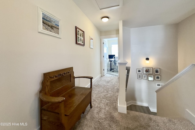 hall with carpet, baseboards, and an upstairs landing