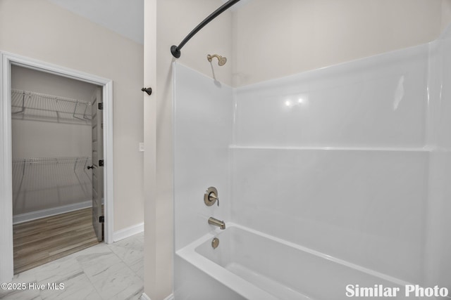 full bath featuring bathing tub / shower combination, marble finish floor, and baseboards