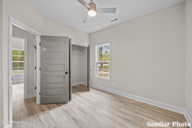 unfurnished bedroom featuring multiple windows, baseboards, light wood finished floors, and lofted ceiling