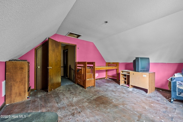 additional living space with visible vents, a textured ceiling, baseboards, and lofted ceiling