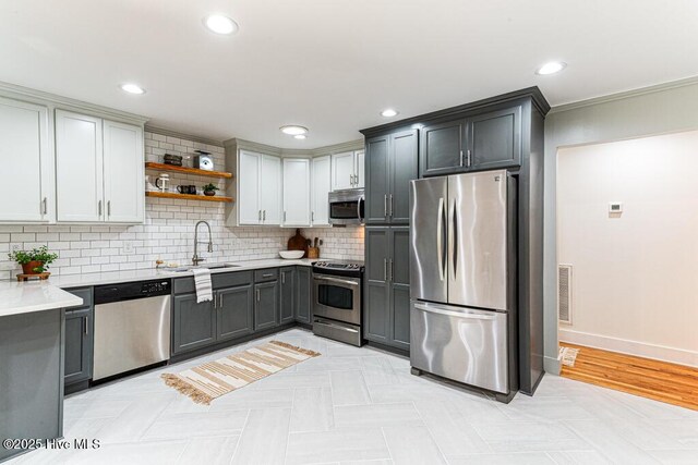1369 Linden Rd, Aberdeen, NC 28315 - kitchen with appliances with stainless steel finishes, open shelves, a sink, light countertops, and backsplash