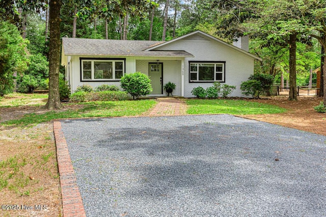 1369 Linden Rd, Aberdeen, NC 28315 - view of front of home with brick siding, a chimney, a front lawn, and a shingled roof