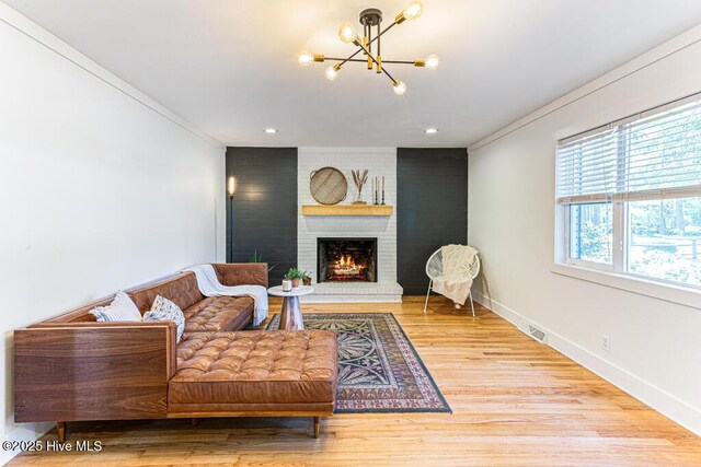 1369 Linden Rd, Aberdeen, NC 28315 - living room featuring a chandelier, a brick fireplace, wood finished floors, crown molding, and baseboards