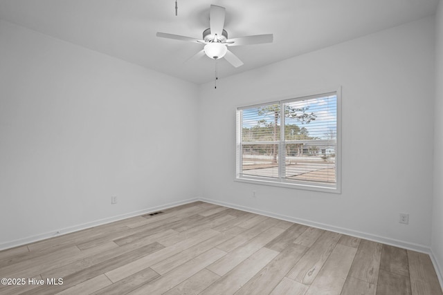 spare room featuring visible vents, ceiling fan, light wood finished floors, and baseboards