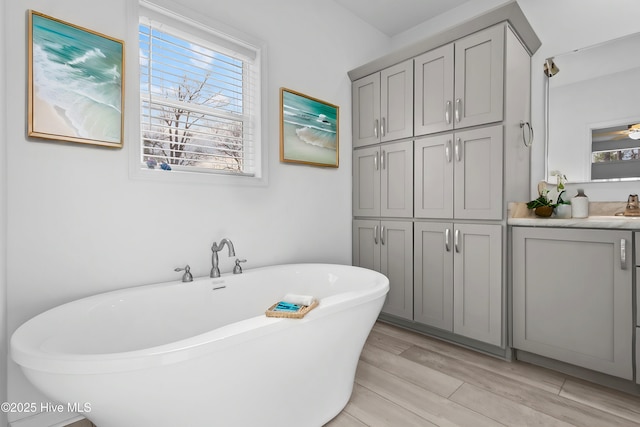 full bath featuring a freestanding bath, wood finished floors, and vanity