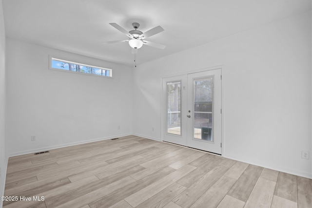 empty room with visible vents, a ceiling fan, and wood finished floors