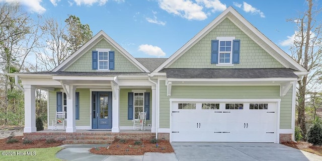 craftsman-style home with concrete driveway, an attached garage, covered porch, and roof with shingles
