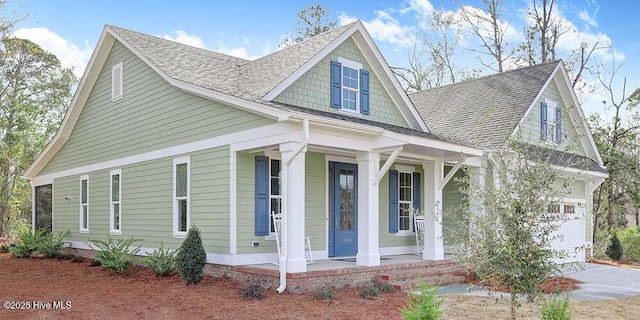 view of front facade featuring roof with shingles, concrete driveway, and a porch