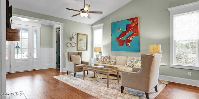 living area featuring lofted ceiling, ceiling fan, wood finished floors, and baseboards