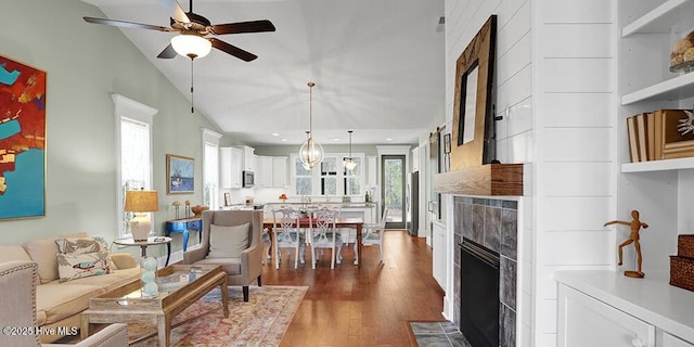 living area with a tiled fireplace, plenty of natural light, and dark wood-style floors