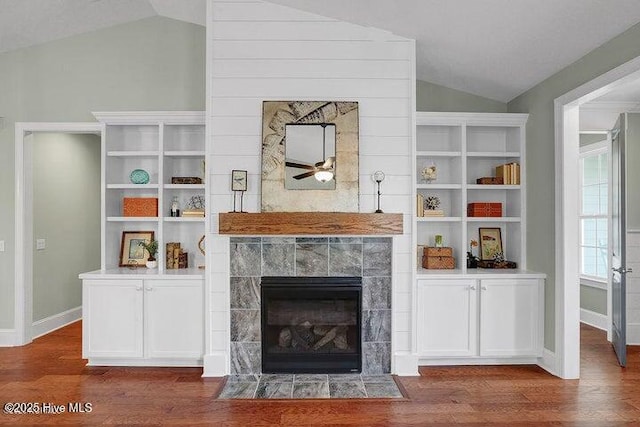 living room featuring a fireplace, a ceiling fan, vaulted ceiling, baseboards, and wood finished floors