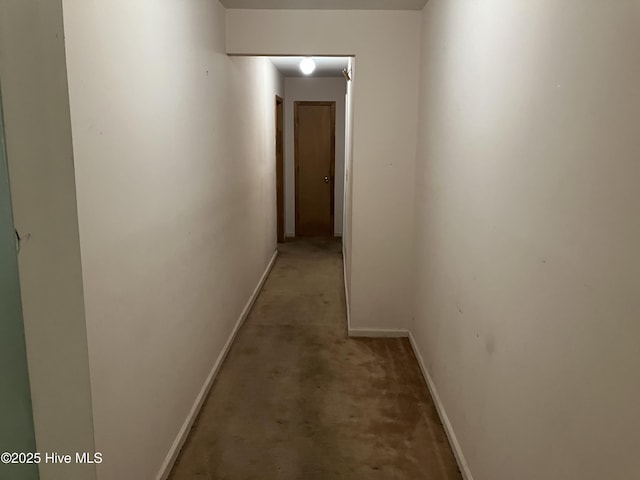 hallway featuring baseboards and light colored carpet