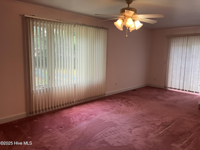 carpeted empty room with ceiling fan and baseboards