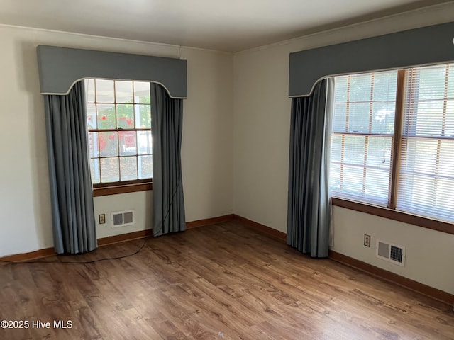 empty room with light wood-style floors, baseboards, and ornamental molding