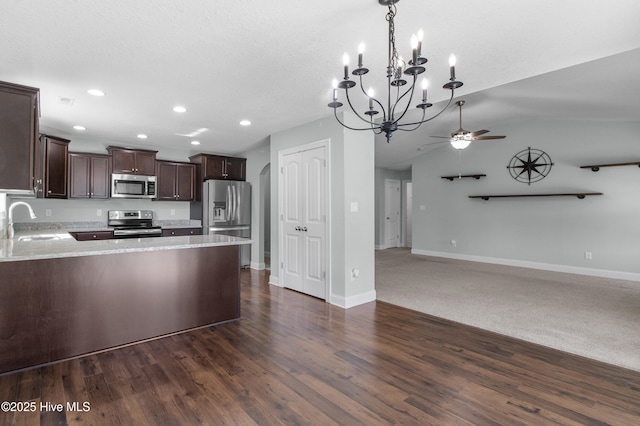 kitchen with dark brown cabinets, open floor plan, appliances with stainless steel finishes, and a sink