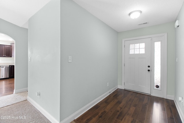 entrance foyer featuring visible vents, arched walkways, and baseboards