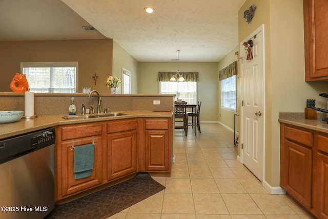 kitchen featuring brown cabinetry, stainless steel dishwasher, a sink, and light tile patterned flooring