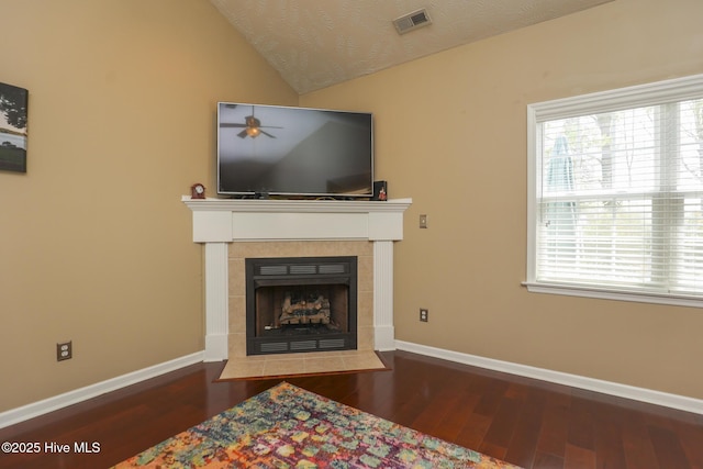 living room featuring vaulted ceiling, wood finished floors, visible vents, baseboards, and a fireplace