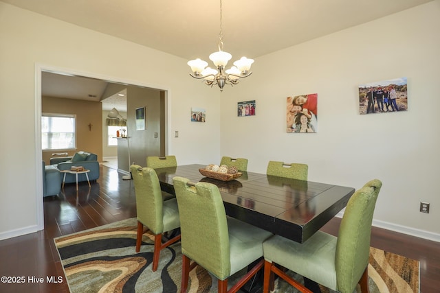 dining area featuring wood finished floors, baseboards, and an inviting chandelier