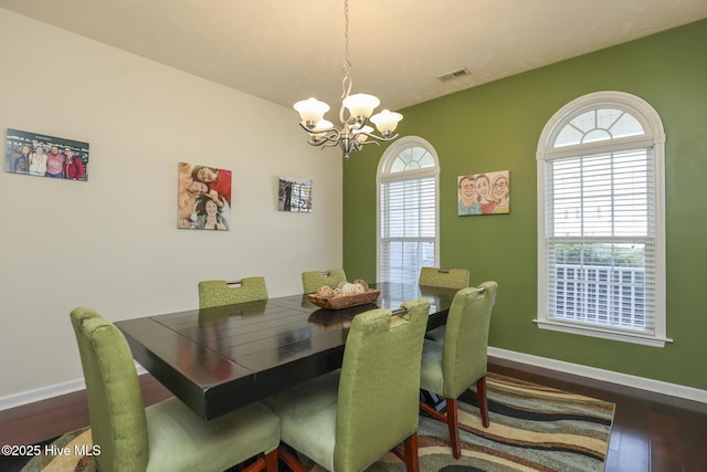 dining area featuring wood finished floors, visible vents, baseboards, and an inviting chandelier