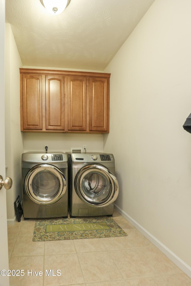 laundry area with tile patterned floors, baseboards, washer and dryer, and cabinet space
