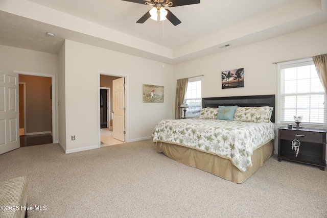 carpeted bedroom featuring ceiling fan, baseboards, and a tray ceiling